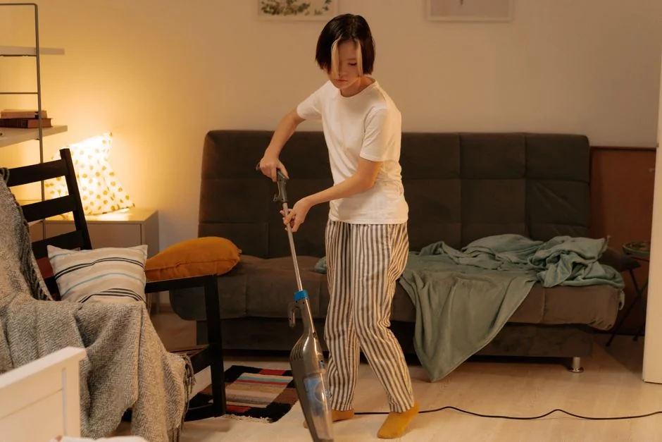 A smiling couple is arranging a sofa in their new home, with moving boxes all around them.